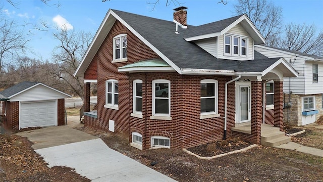 view of front facade with brick siding, an outdoor structure, a detached garage, concrete driveway, and a chimney