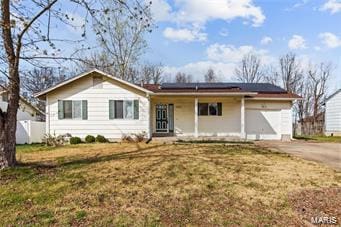 single story home with solar panels, a porch, an attached garage, a front yard, and driveway