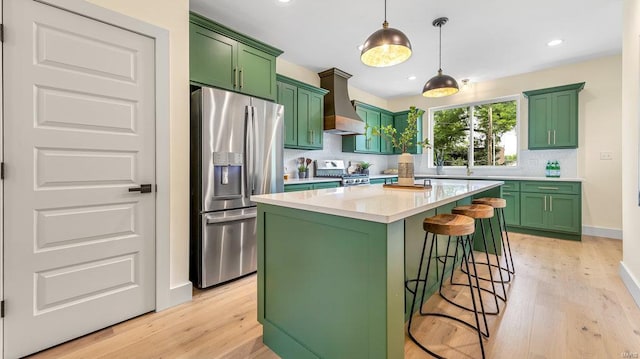 kitchen with stove, a kitchen island, light countertops, custom exhaust hood, and stainless steel fridge