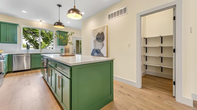 kitchen with light countertops, visible vents, green cabinets, stainless steel dishwasher, and a kitchen island