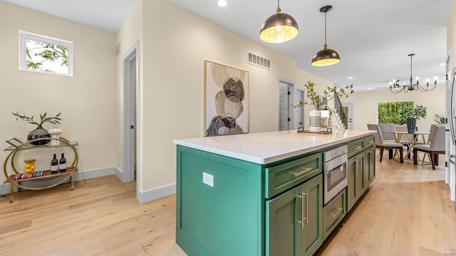 kitchen featuring a center island, light countertops, hanging light fixtures, visible vents, and green cabinets