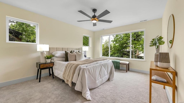 bedroom with light carpet, ceiling fan, visible vents, and baseboards