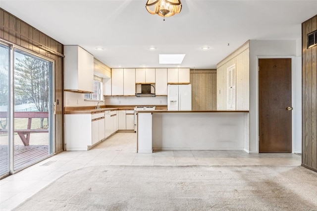 kitchen with light carpet, a peninsula, white refrigerator with ice dispenser, and stove