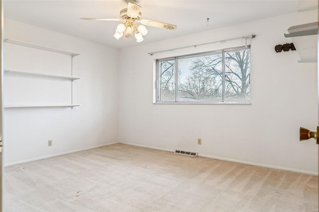 carpeted spare room with baseboards, visible vents, and a ceiling fan