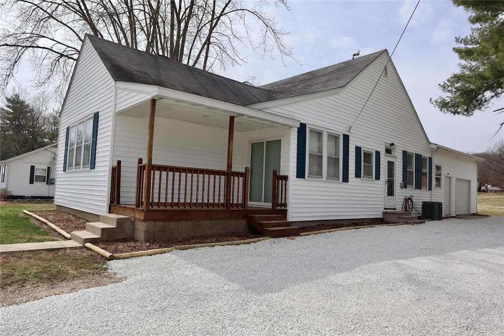 view of front facade featuring cooling unit, covered porch, and roof with shingles