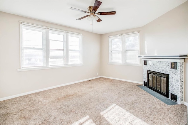 unfurnished living room with a wealth of natural light, baseboards, ceiling fan, and a premium fireplace