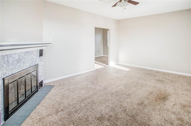 unfurnished living room featuring a tile fireplace, baseboards, a ceiling fan, and dark colored carpet