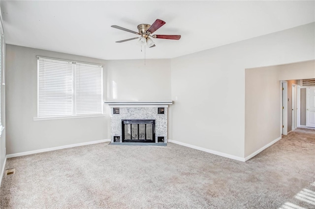 unfurnished living room with visible vents, a fireplace with flush hearth, carpet flooring, baseboards, and ceiling fan