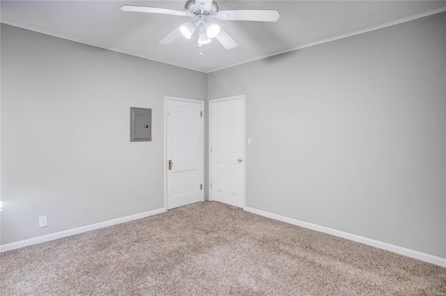 spare room featuring a ceiling fan, electric panel, carpet, and baseboards