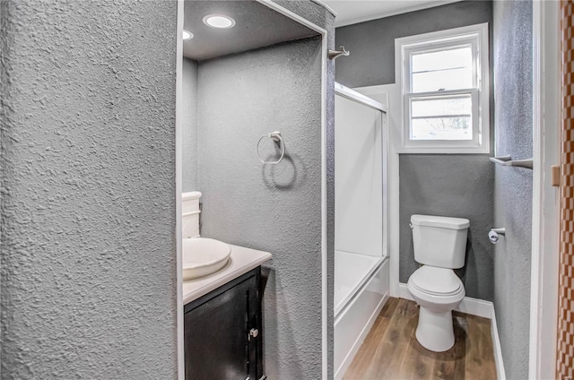 bathroom featuring vanity, wood finished floors, baseboards, toilet, and a textured wall