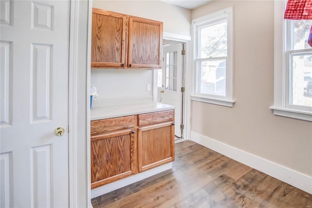 kitchen featuring plenty of natural light, light countertops, light wood-type flooring, and baseboards