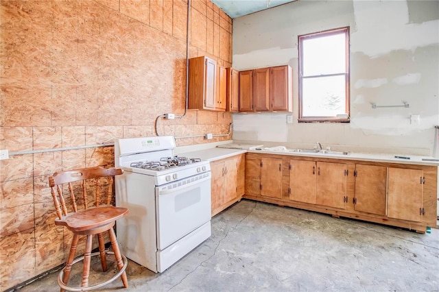 kitchen featuring a sink, concrete flooring, white gas range oven, and light countertops