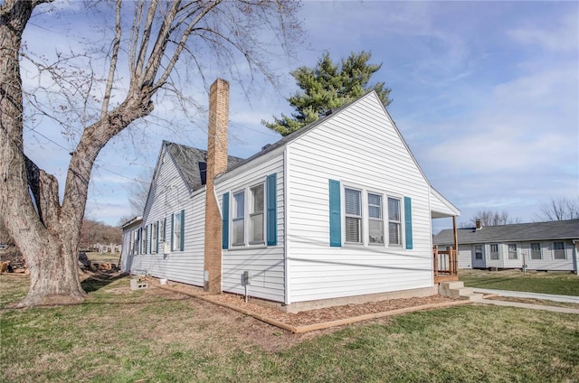 view of side of property featuring a lawn and a chimney