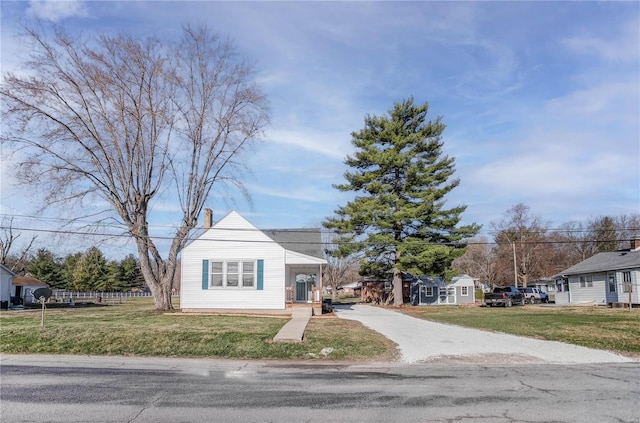 bungalow-style home with a front yard, a residential view, and a chimney