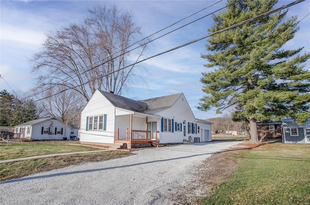 bungalow-style house featuring a front yard, an attached garage, covered porch, and driveway