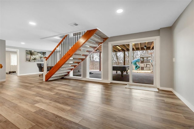 interior space featuring a healthy amount of sunlight, stairway, visible vents, and wood finished floors