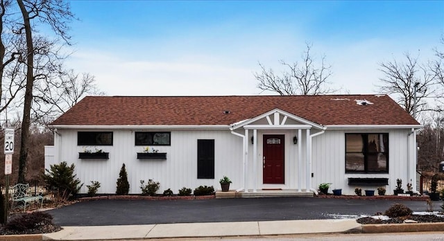 view of front of house featuring driveway and roof with shingles