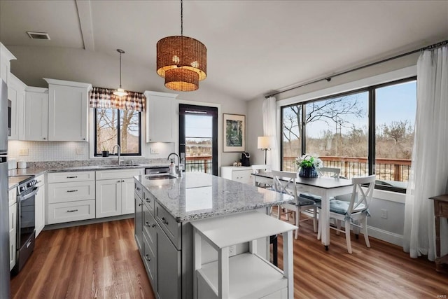 kitchen with lofted ceiling, visible vents, wood finished floors, and range with electric stovetop