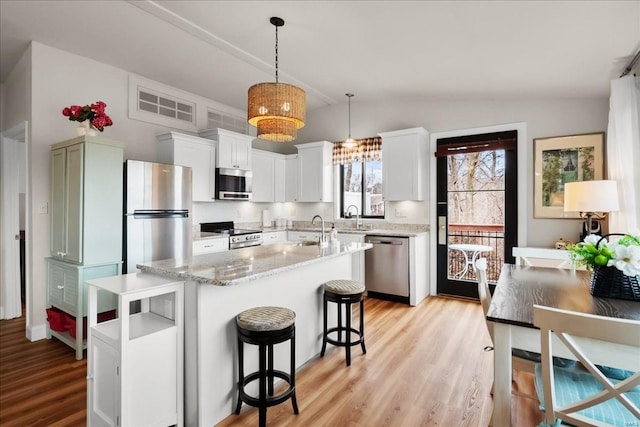 kitchen with lofted ceiling, light wood-style flooring, appliances with stainless steel finishes, and a sink