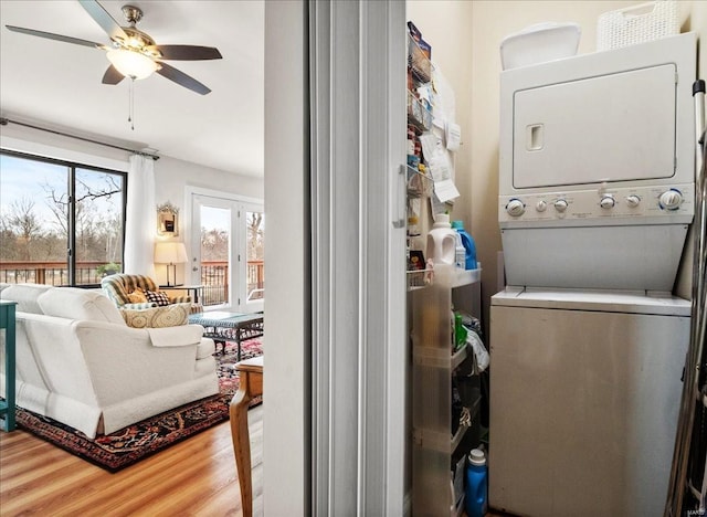 laundry area featuring stacked washer / drying machine, laundry area, ceiling fan, and wood finished floors