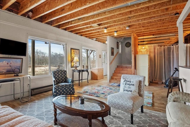 living area with stairs, baseboard heating, and wood finished floors