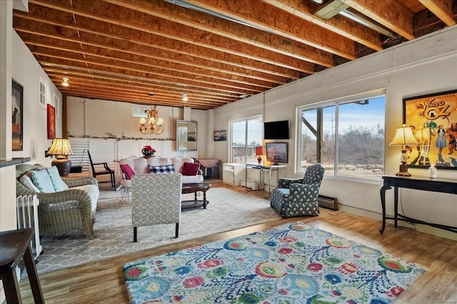 living area with a baseboard heating unit, a chandelier, and wood finished floors