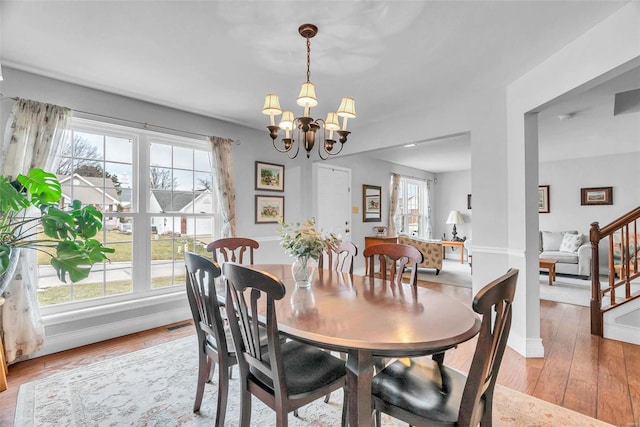 dining space featuring stairs, a notable chandelier, baseboards, and wood finished floors