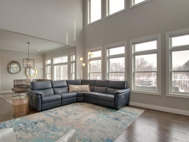 living area with baseboards, wood finished floors, visible vents, and crown molding