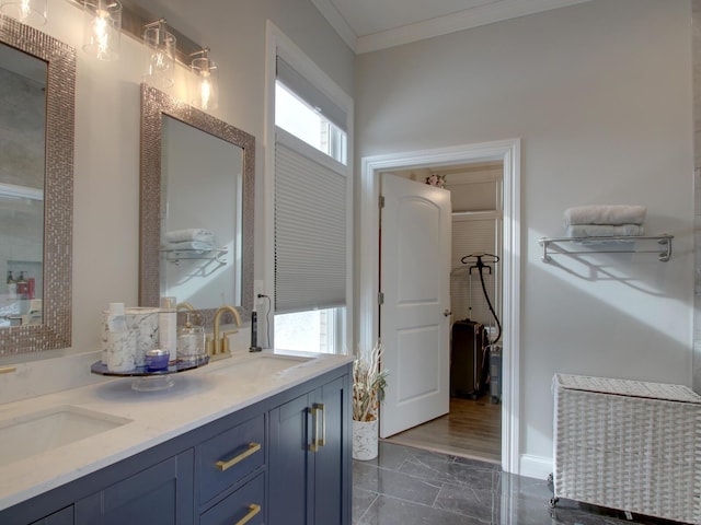 bathroom with marble finish floor, double vanity, a sink, and crown molding