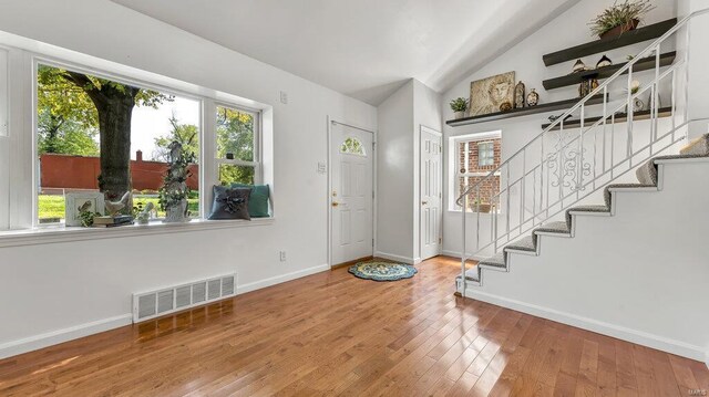 entryway featuring vaulted ceiling, stairway, wood finished floors, and visible vents