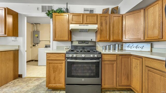 kitchen with under cabinet range hood, stainless steel gas range oven, washer / clothes dryer, and light countertops