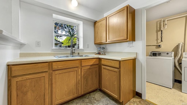 kitchen with light countertops, brown cabinets, a sink, and washer and dryer