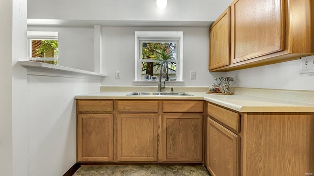 kitchen featuring light countertops, a sink, and brown cabinets