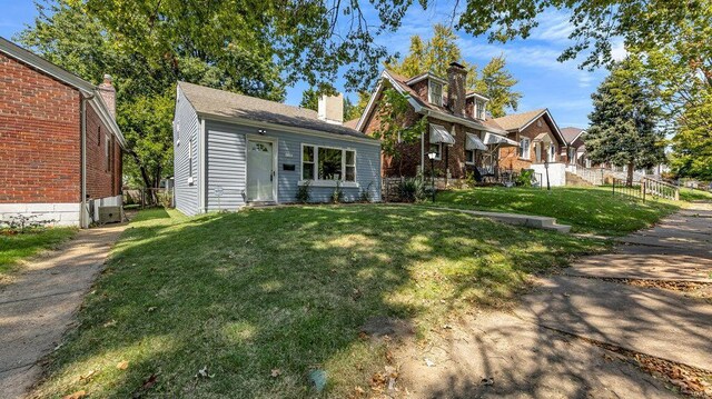 view of front facade featuring a front yard, fence, and a chimney