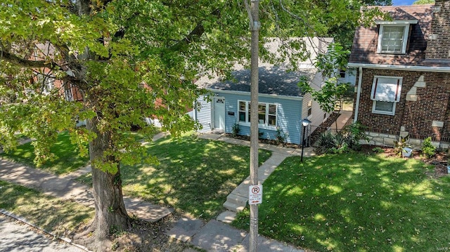 view of front of home featuring entry steps, brick siding, roof with shingles, and a front yard