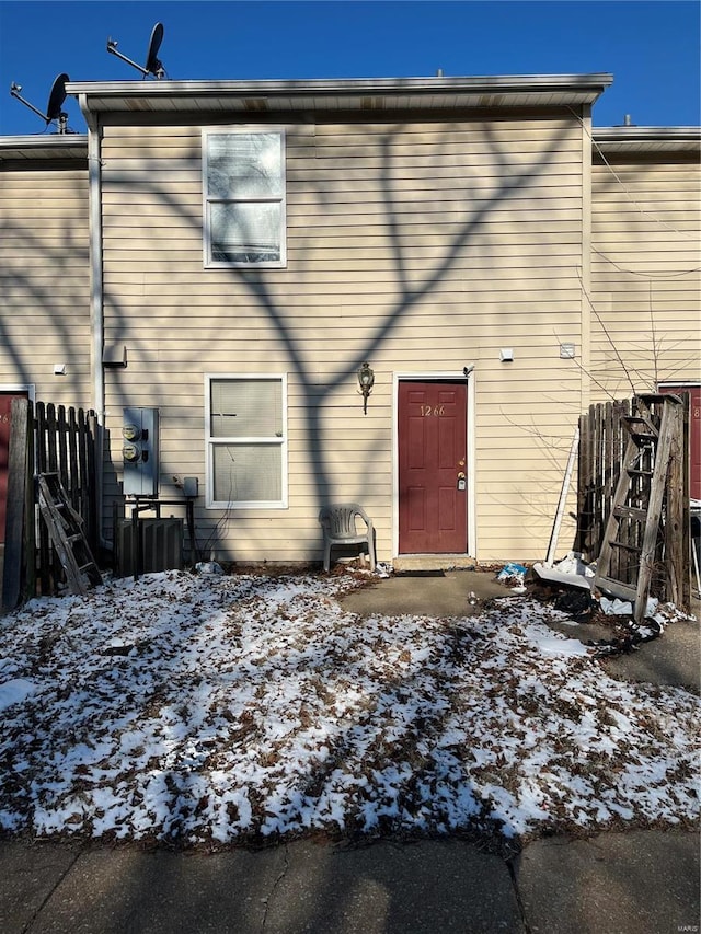 snow covered back of property with central AC unit and fence