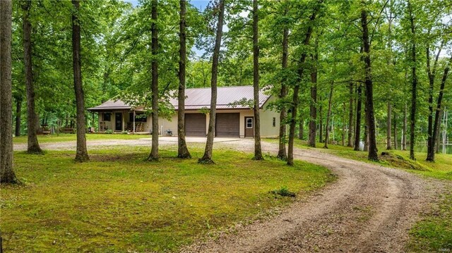 ranch-style house featuring dirt driveway, metal roof, and an attached garage
