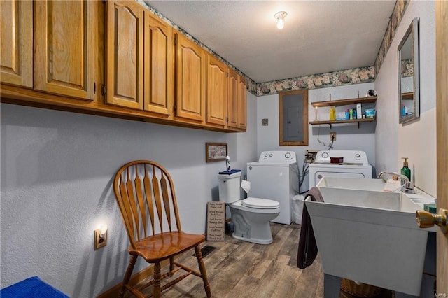 washroom with laundry area, a sink, wood finished floors, electric panel, and washer and clothes dryer