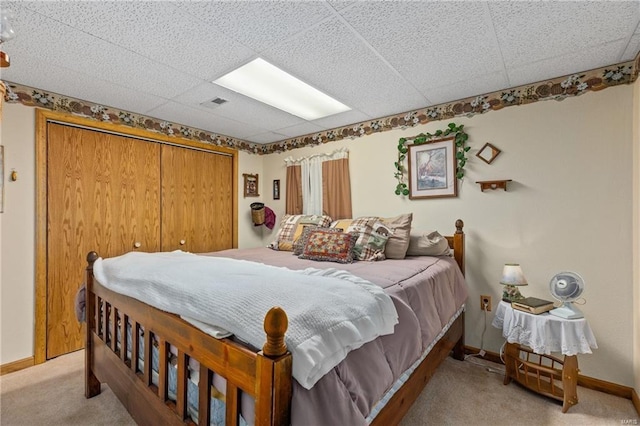 bedroom with a drop ceiling, light carpet, visible vents, baseboards, and a closet