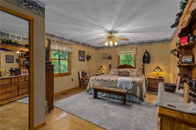 bedroom with a ceiling fan, multiple windows, visible vents, and a textured ceiling