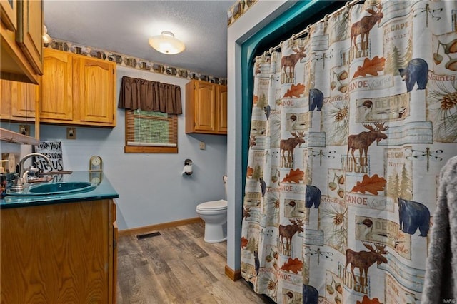 full bath featuring visible vents, toilet, vanity, wood finished floors, and baseboards