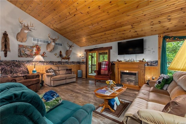 living room featuring visible vents, wainscoting, a glass covered fireplace, wood ceiling, and wood finished floors