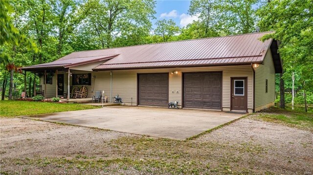 view of front of home featuring a garage, concrete driveway, metal roof, and covered porch