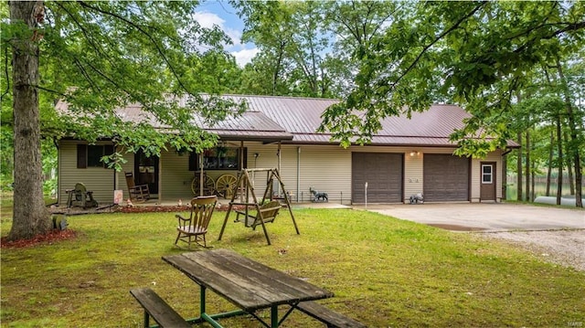 ranch-style home featuring metal roof, driveway, a front lawn, and an attached garage