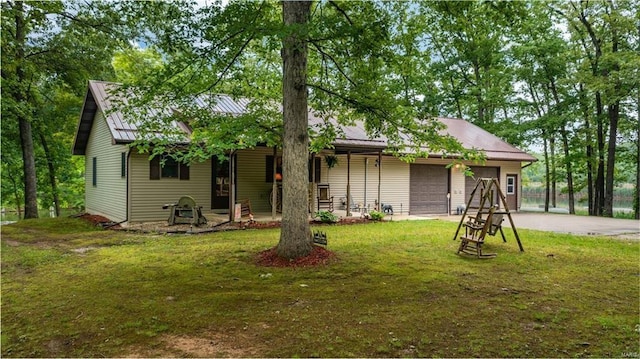 ranch-style home with a garage, concrete driveway, metal roof, and a front lawn