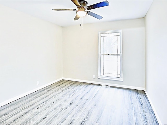 empty room featuring visible vents, light wood-type flooring, a ceiling fan, and baseboards