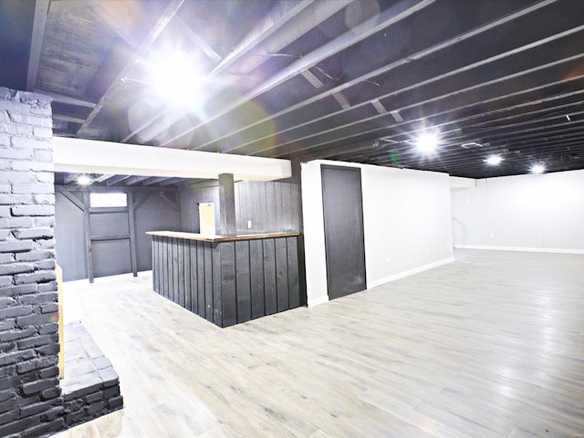 finished basement featuring a bar, wood finished floors, and baseboards