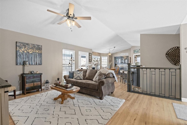 living room with ceiling fan, baseboards, vaulted ceiling, and wood finished floors