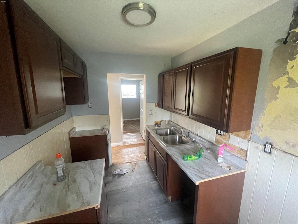 kitchen with backsplash, dark brown cabinetry, light countertops, and a sink