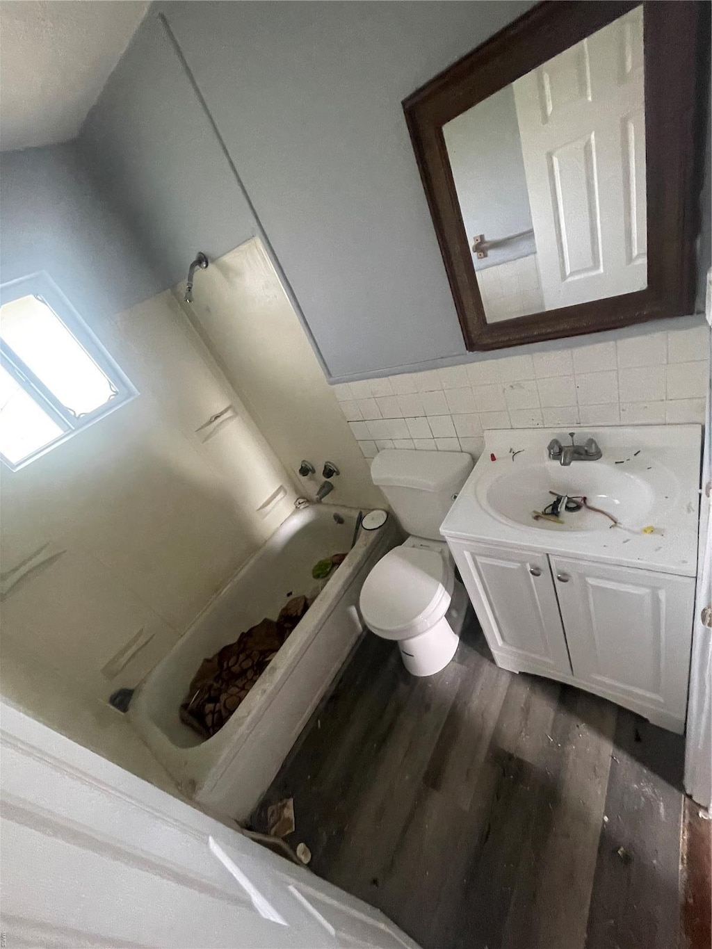 full bath with wood finished floors, vanity, tile walls, toilet, and wainscoting